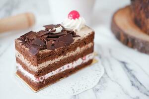 chocola taart met geslagen room en kersen Aan wit marmeren achtergrond foto