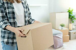 in beweging huis, verhuizing. vrouw hand- Holding karton doos Aan nieuw appartement, binnen de kamer was een karton doos met persoonlijk bezittingen en meubilair. Actie in de huis of condominium foto