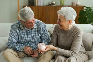 besparing geld investering voor toekomst. senior volwassen volwassen paar Holding varkentje bank zetten geld munt. oud Mens vrouw tellen besparing geld planning pensioen begroting. besparing investering bank concept. foto