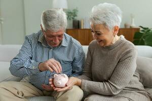 besparing geld investering voor toekomst. senior volwassen volwassen paar Holding varkentje bank zetten geld munt. oud Mens vrouw tellen besparing geld planning pensioen begroting. besparing investering bank concept. foto