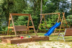lege moderne houten kinderspeelplaats ingesteld op groene tuin in openbaar park in zomerdag. grappig speelgoedland voor kinderen. stedelijke bewegingsactiviteiten voor kinderen buitenshuis. buurt jeugd concept. foto
