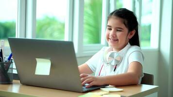 kind meisje glimlach genieten e-learning Aan computer notitieboekje met voor lach naar grappig communicatie en studie online of leren van huis naar Speel laptop door terug naar school- foto