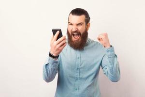 foto van boze bebaarde zakenman die schreeuwt tegen smartphone