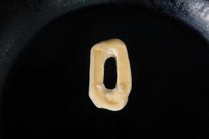boter in de vorm van nummer 0 op hete pan - close-up bovenaanzicht