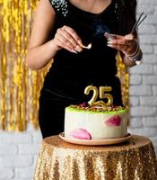 vrouw die haar verjaardag viert en de kaarsjes op de taart aansteekt