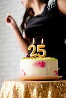 vrouw in zwarte feestjurk die kaarsen aansteekt op verjaardagstaart