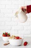 ontbijtgranen, verse aardbeien en melk in een kom foto
