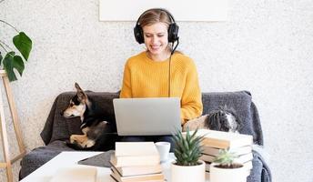 jonge lachende vrouw in zwarte koptelefoon die online studeert met behulp van laptop foto