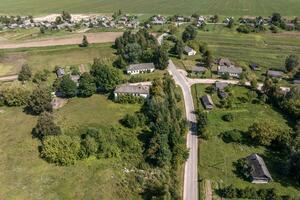 panoramisch antenne visie van eco dorp met houten huizen, grind weg, tuinen en boomgaarden foto