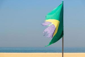 vervaagde en gescheurde vlag van Brazilië buiten op het strand van Copacabana foto