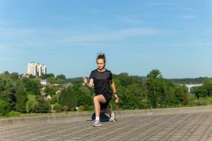 jong, fit en sportief meisje in zwart kleren uitrekken na de training in de stedelijk stad park. foto