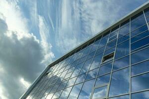 bouwkundig detail van de facade met meerdere reflecties van bewolkt lucht en de zon. foto