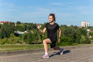 jong, fit en sportief meisje in zwart kleren uitrekken na de training in de stedelijk stad park. foto