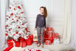 wit lang haren meisje siert een kamer met Kerstmis speelgoed. foto