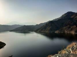 een mooi dag visie van wadi qanuna dam in al Bah, saudi Arabië. de water van de dam en de omgeving heuvels zijn presenteren een mooi tafereel in de zonlicht. foto