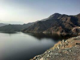 een mooi dag visie van wadi qanuna dam in al Bah, saudi Arabië. de water van de dam en de omgeving heuvels zijn presenteren een mooi tafereel in de zonlicht. foto