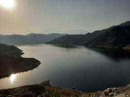 een mooi dag visie van wadi qanuna dam in al Bah, saudi Arabië. de water van de dam en de omgeving heuvels zijn presenteren een mooi tafereel in de zonlicht. foto