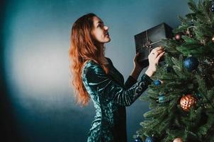 mooie vrouw kerstboom versieren met een geschenkdoos gift foto