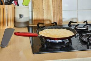 Koken crêpe suzette pannekoeken in frituren pan Aan gas- fornuis foto