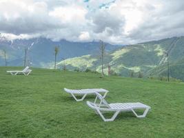 witte plastic ligstoelen op de groene weide bij het hotel foto