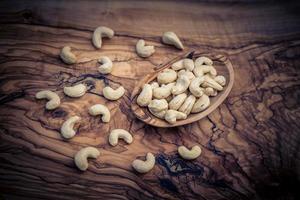 een stapel cashewnoten op olijfhout foto