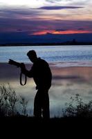 een fotograaf silhouet in de buurt van de kust foto