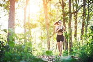 jonge vrouw joggen op landelijke weg in de natuur van het groene bos. foto