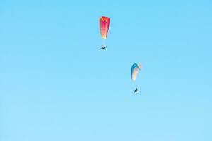 twee kleurrijk paragliders stijgend door de blauw lucht foto