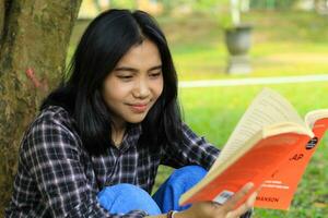 gelukkig en succes vrouw Aziatisch college leerling genieten van lezen een boek in de park foto
