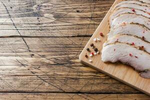 stukken van gerookt gekookt varkensvlees Aan een houten rustiek bord met brood, sauzen en specerijen Aan een houten tafel. kopiëren ruimte foto