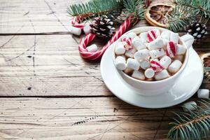 een kop van heet chocola met marshmallows. Kerstmis boom en decoraties, riet karamel en sinaasappels noten houten achtergrond kopiëren ruimte. foto