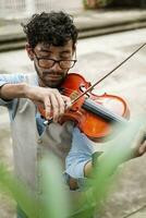 knap Mens in hesje spelen viool buitenshuis. dichtbij omhoog van violist Mens spelen een melodie buitenshuis. violist artiest spelen een melodie buitenshuis. foto