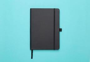 zwarte notebook geïsoleerd op blauwe achtergrond foto