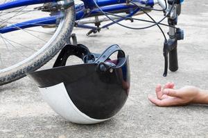 fiets en een helm die met de hand op de weg ligt foto