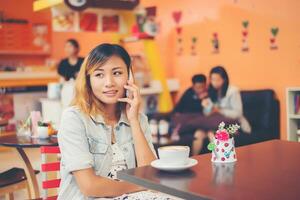 jonge mooie vrouw pratende telefoon bij coffeeshop ziet er zo blij uit. foto