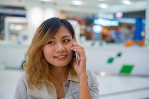 mooie jonge vrouw praten aan de telefoon in het winkelcentrum. foto