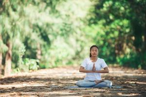 jonge aziatische vrouw die 's ochtends yoga doet in het park. gezond