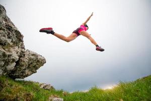 sprong van een sportieve vrouwelijke atleet die in de bergen loopt foto