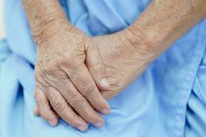 Aziatische oudere senior vrouw patiënt zittend op bed in het ziekenhuis, close-up bij haar hand. foto