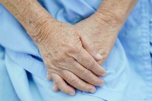 Aziatische oudere senior vrouw patiënt zittend op bed in het ziekenhuis, close-up bij haar hand. foto