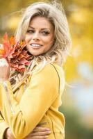 herfst portret van jong vrouw met boeket van esdoorn- bladeren foto