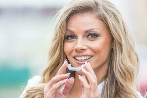 invisalign orthodontie concept - jong aantrekkelijk vrouw Holding - gebruik makend van onzichtbaar een beugel of trainer foto