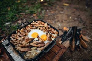gebakken eieren en gegrild varkensvlees in een camping pan foto