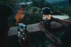 lantaarn Aan de balkon, hand is verlichting een lantaarn Aan de balkon Bij schemering. foto