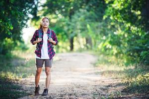 jonge vrouw wandelaar met rugzak wandelen en glimlachen op een landweg foto