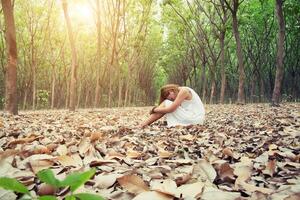 jonge Aziatische vrouw zit helaas alleen op droog blad in het bos foto