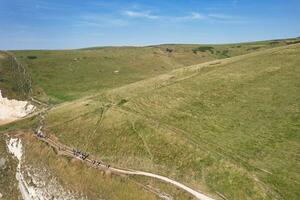 hoog hoek visie van mensen zijn naderen naar gedurfd deur strand welke is meest beroemd toerist attractie plaats door wandelen afstand over- landschap en heuvels. gevangen genomen Aan september 9e, 2023 foto