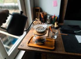 druppelkoffie in huis, een heet water over een druppelkoffie gieten foto