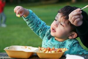 schattig Aziatisch Pakistaans baby jongen is aan het eten in een lokaal afweren openbaar park van luton stad, Engeland uk. beeld gevangen genomen Aan juli 23e, 2023 foto