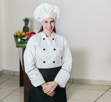 portret van een vrouw voedingsdeskundige in uniform met vers groenten Aan de tafel, een vrouw voedingsdeskundige met een tafel van groenten, portret van een vrouw chef omringd door vers groenten foto